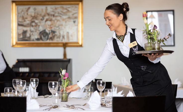 student putting flowers on a table in restaurant