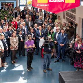 image taken from upper balcony looking down at a presentaiton. lots of people gathered in the atrium