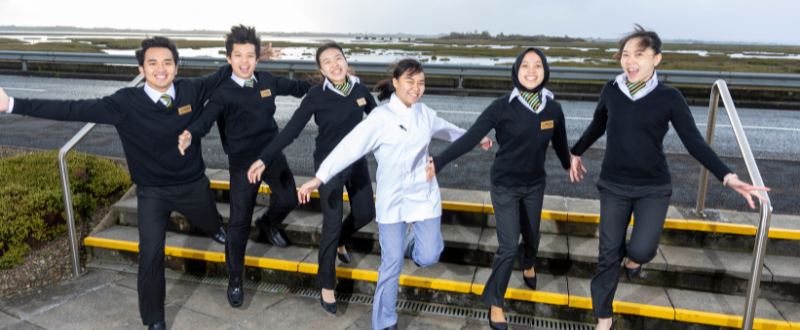 Study Abroad programme with indonesian students jumping and smiling outside college 