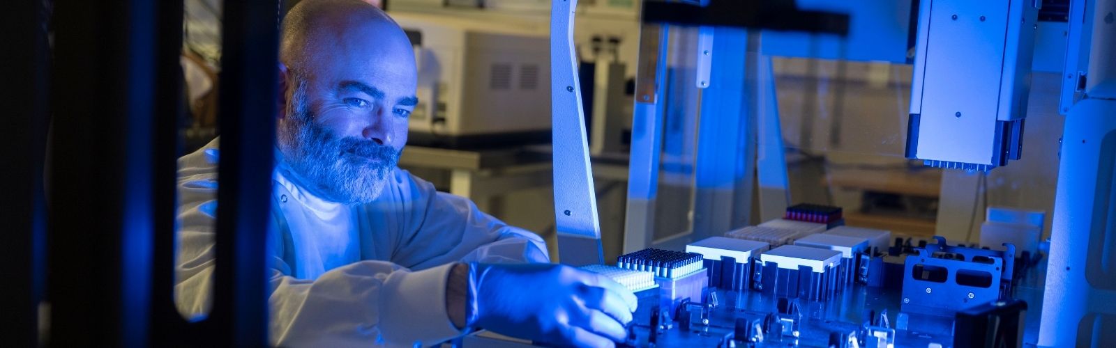 A person in a labcoat placing a rack into a handling system